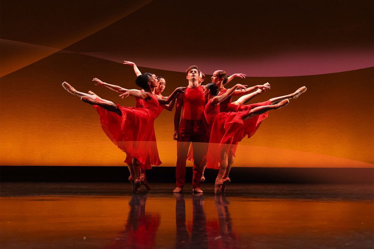 Northern Ballet group with legs outstretched against red background