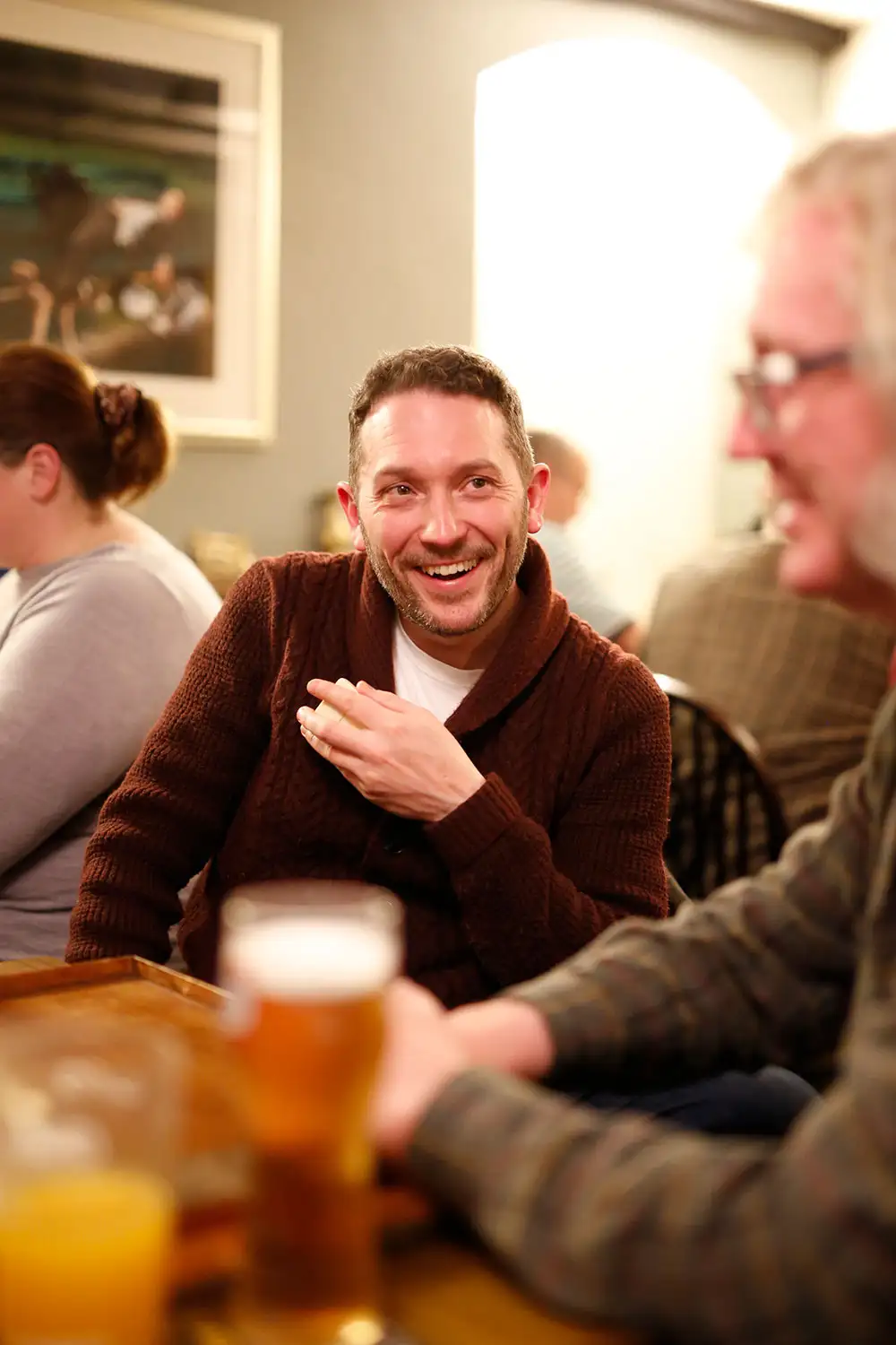 A warm pub interior in Fadmoor, featuring patrons enjoying drinks and engaging in lively conversation.