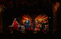 A jazz band performs on stage in a vibrant venue, with colorful lights and an intimate audience enjoying the music.