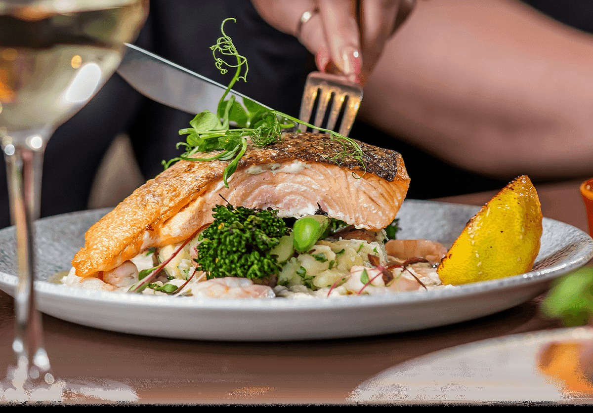 Grilled salmon fillet with lemon, greens, and vegetables