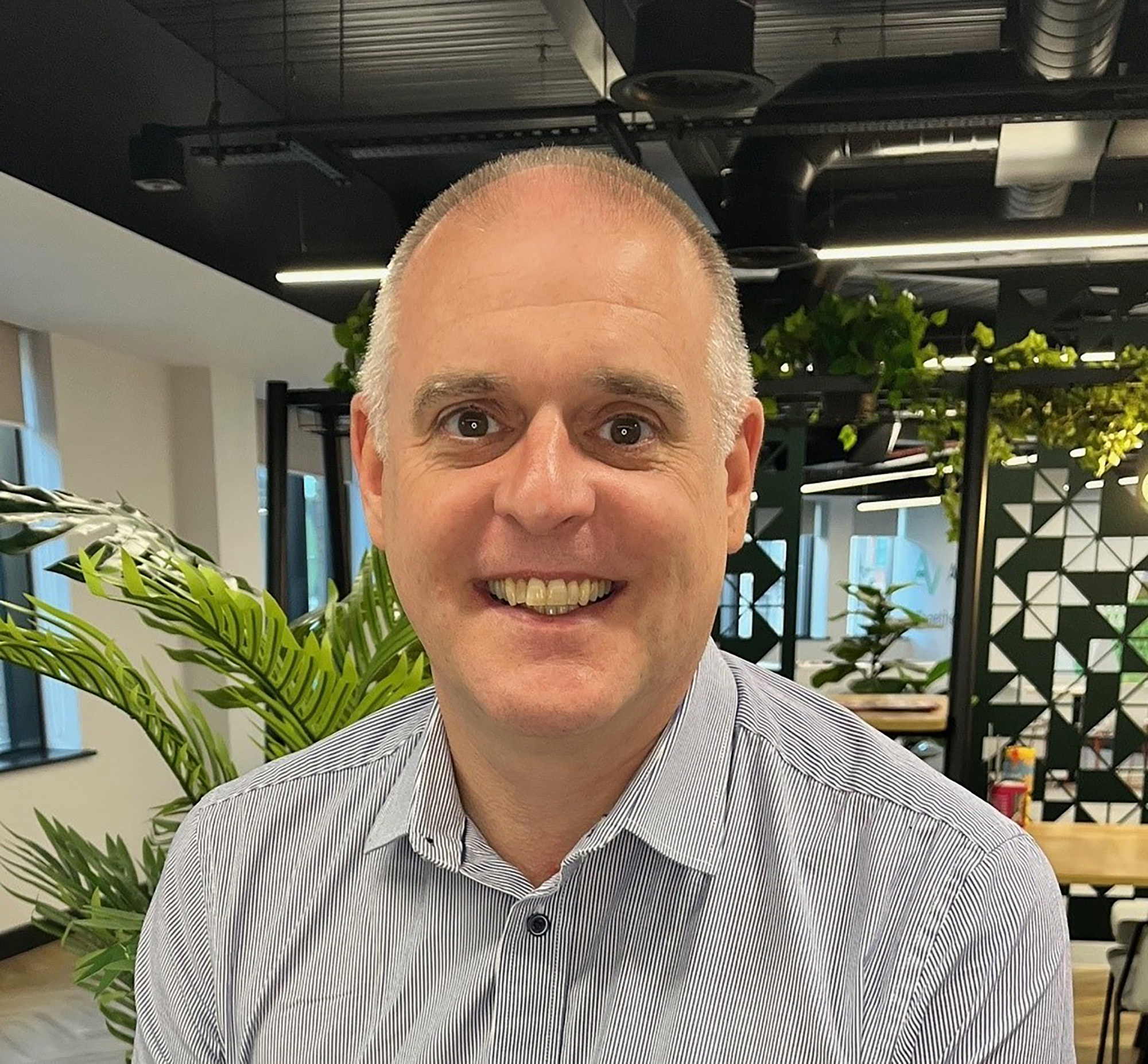Man smiling in modern office with plants and geometric decor