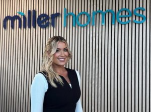 Blonde woman smiles warmly against a stylish wooden wall with 