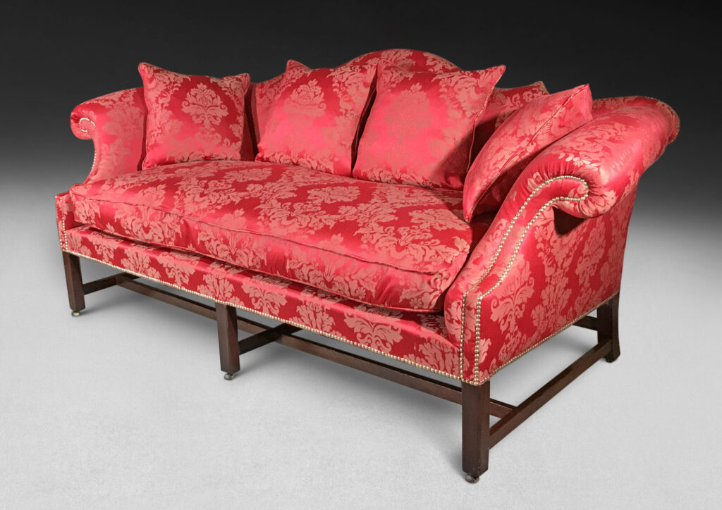 Elegant red sofa with intricate floral upholstery and plush cushions, set against a dark gradient background.